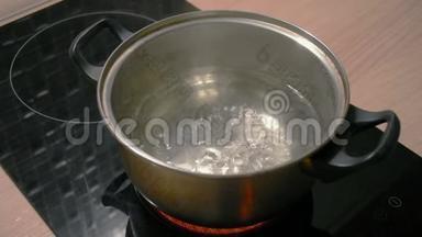 在黑色电磁炉上用金属平底锅煮水。
